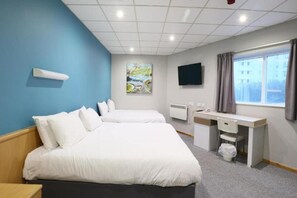 Een hotelkamer met twee bedden, een bureau, een stoel, een televisie en een raam met gordijnen.