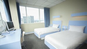 Habitación de hotel con dos camas, un escritorio con computadora y una ventana con cortinas.