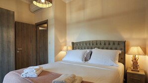 Ein ordentlich bezogenes Bett mit weißen Leinentüchern und gefalteten Handtüchern, ein Holzschrank und ein Nachttisch mit einer Lampe.