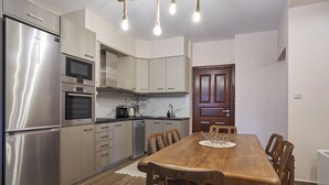 Eine moderne Küche mit Edelstahlgeräten, einem Holzespeisetisch und einer Holztür.