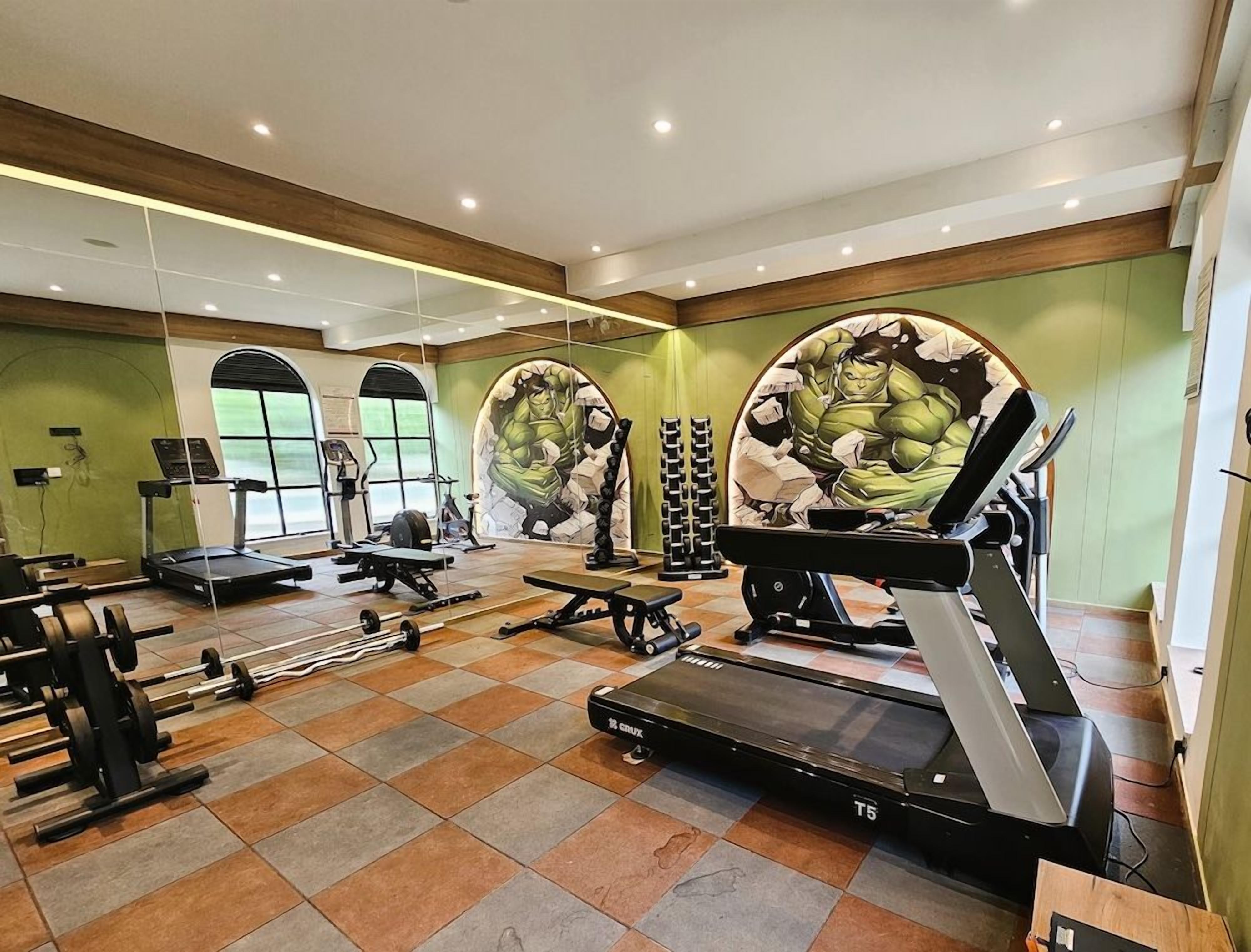 A gym with treadmills, weight machines, and a mirrored wall.