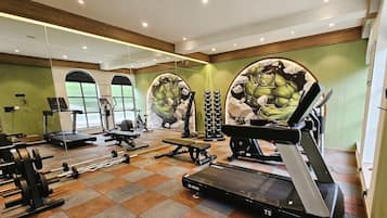 A gym with treadmills, weight machines, and a mirrored wall.