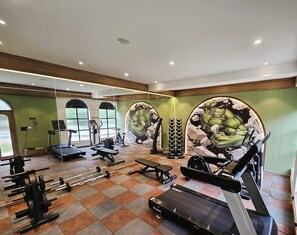 A gym with cardio equipment, weight machines, and a mirrored wall.