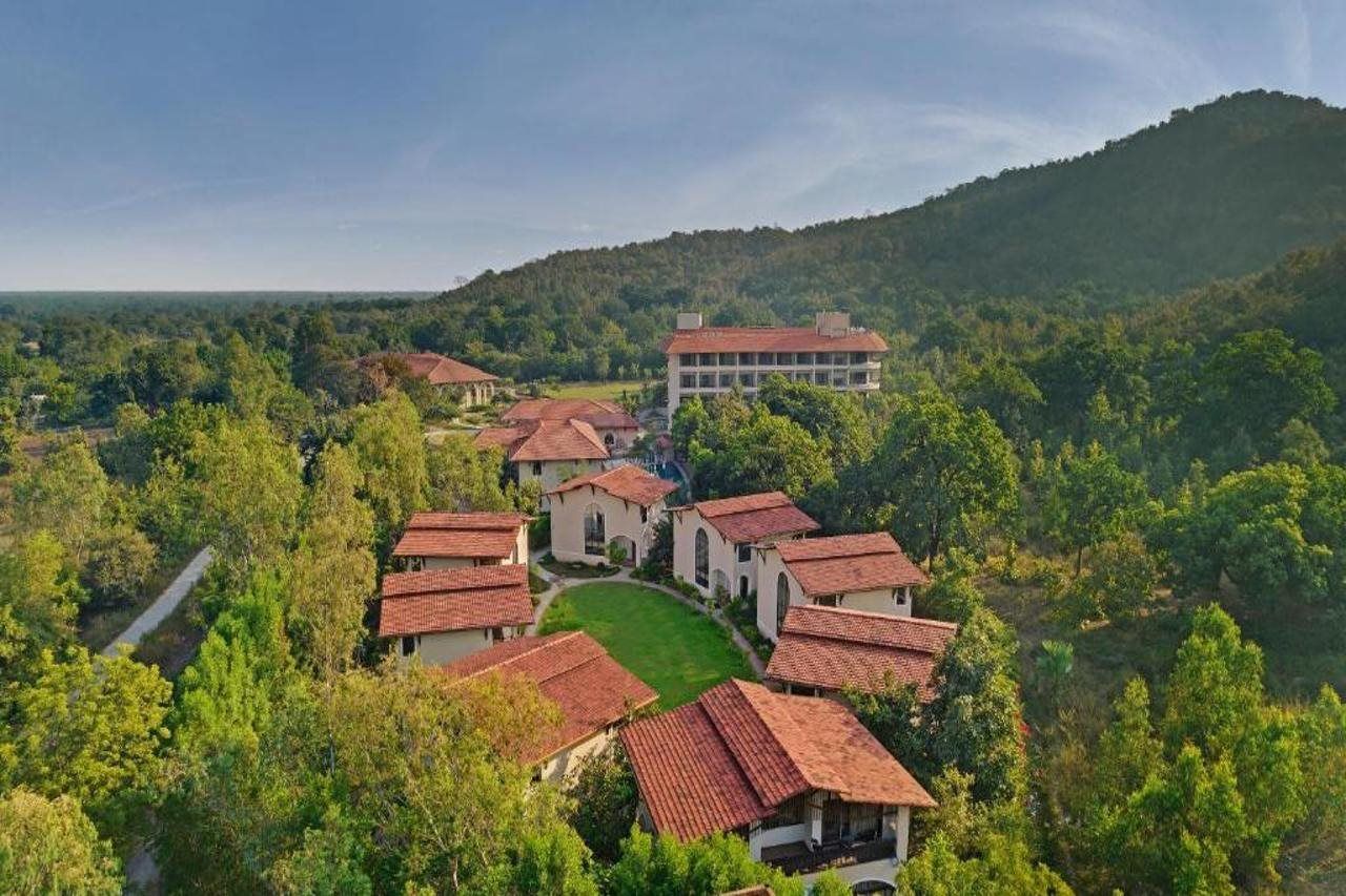 A residential area with multiple buildings, a central courtyard, and a hill in the background.