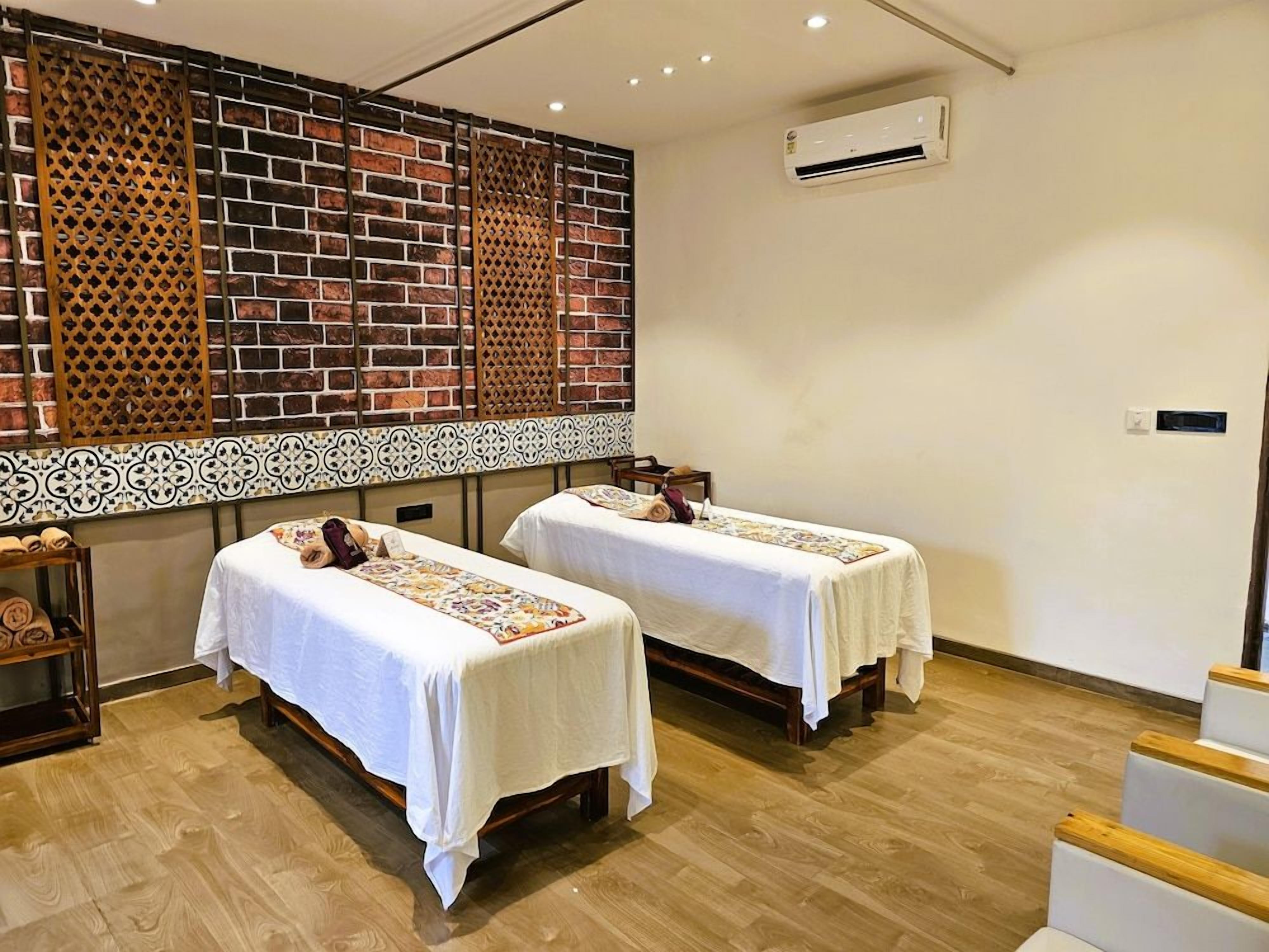 A room with two beds, a brick wall, a decorative screen, and an air conditioning unit.