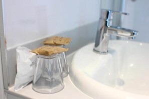 Un lavabo de salle de bain avec un récipient transparent en verre et un sac blanc posé sur le comptoir.