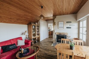 A cozy living room with a red sofa, wooden coffee table, and a fireplace. - Holiday home with sea view, Le Conquet (Le Conquet)