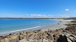 A coastal landscape with a rocky shoreline, a sandy beach, and a clear blue sky.