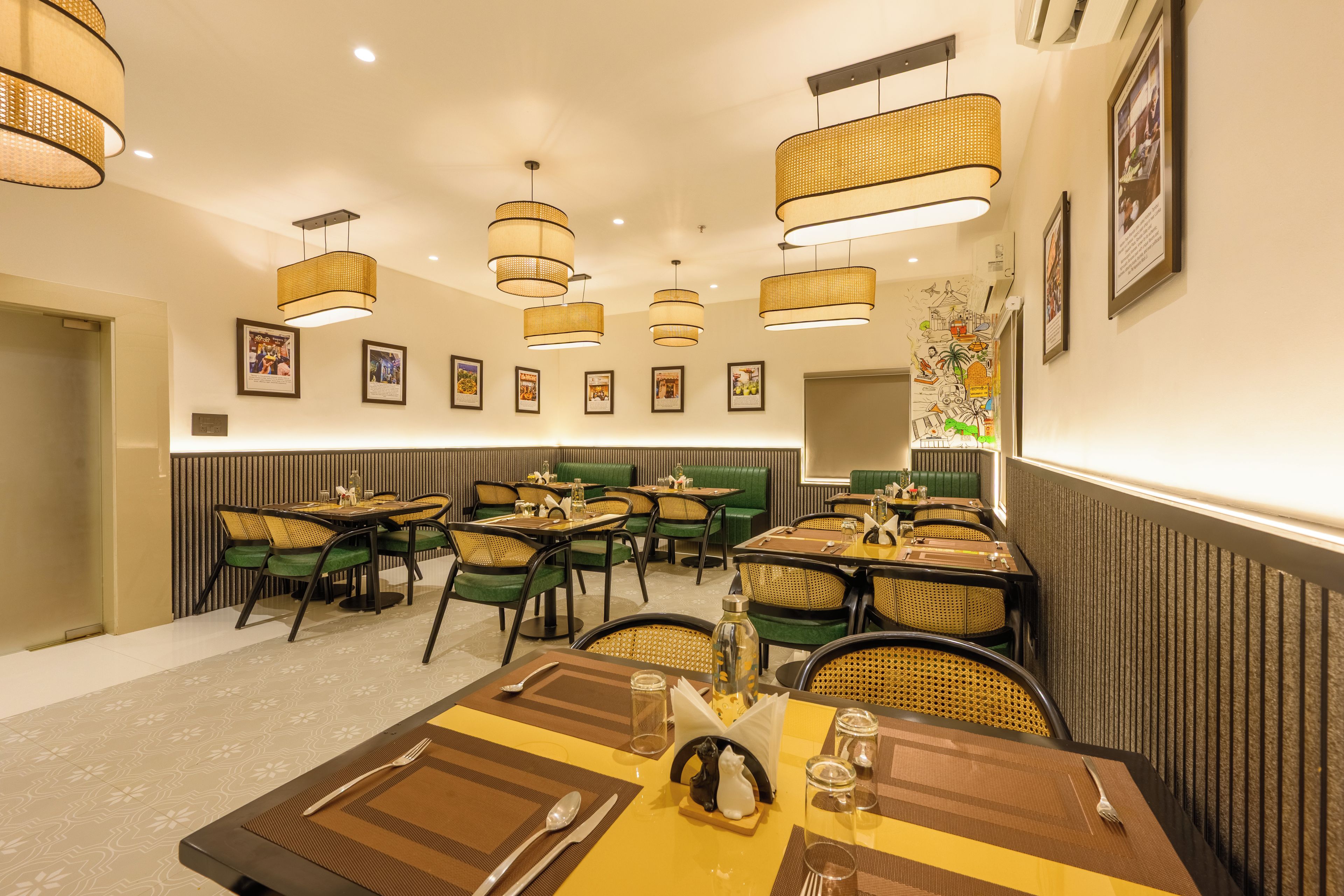 A restaurant with multiple tables and chairs, overhead lighting, and framed pictures on the walls.
