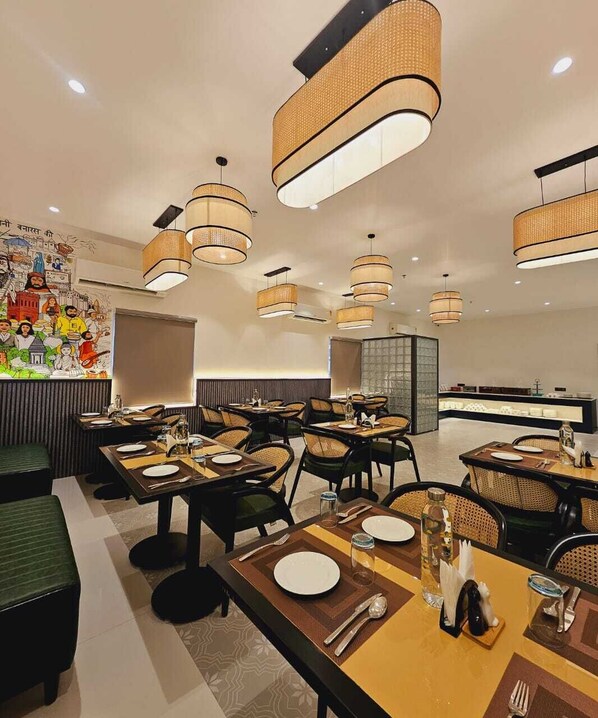 A modern dining area with multiple tables, wicker chairs, and contemporary pendant lighting. - HERITAGE KASHINAAMA EK KAHANI BANARAS KI (Varanasi)