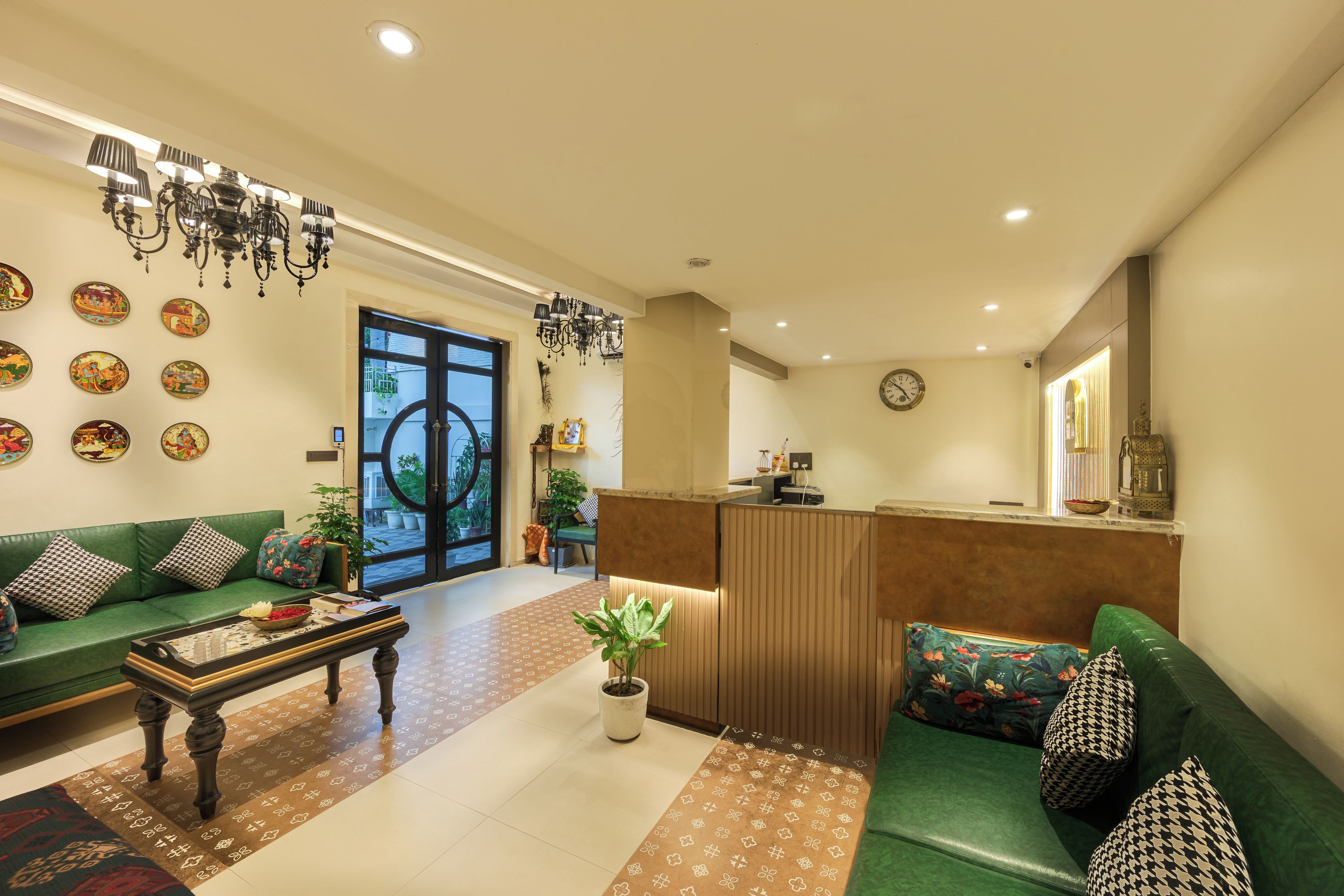 A hotel lobby with a reception desk, green sofas, a coffee table, and decorative wall art.