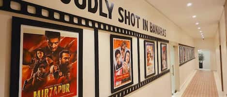 Un couloir orné d’une série d’affiches de films accrochées au mur, d’un tapis à motifs et d’une pancarte sur laquelle on peut lire : « FIER D’AVOIR ÉTÉ TOURÉ À BANARAS ».