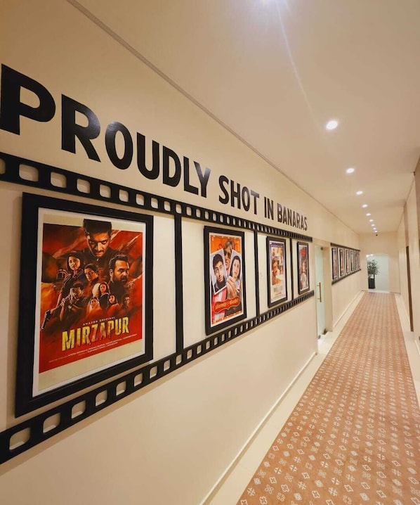 Un pasillo con una serie de carteles de películas en la pared, una alfombra estampada y un letrero que dice