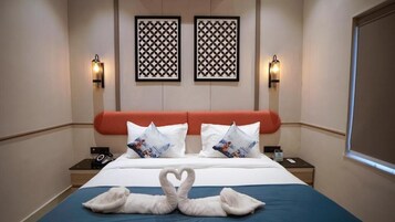 A hotel room with a bed, two wall-mounted light fixtures, and a decorative wall panel.