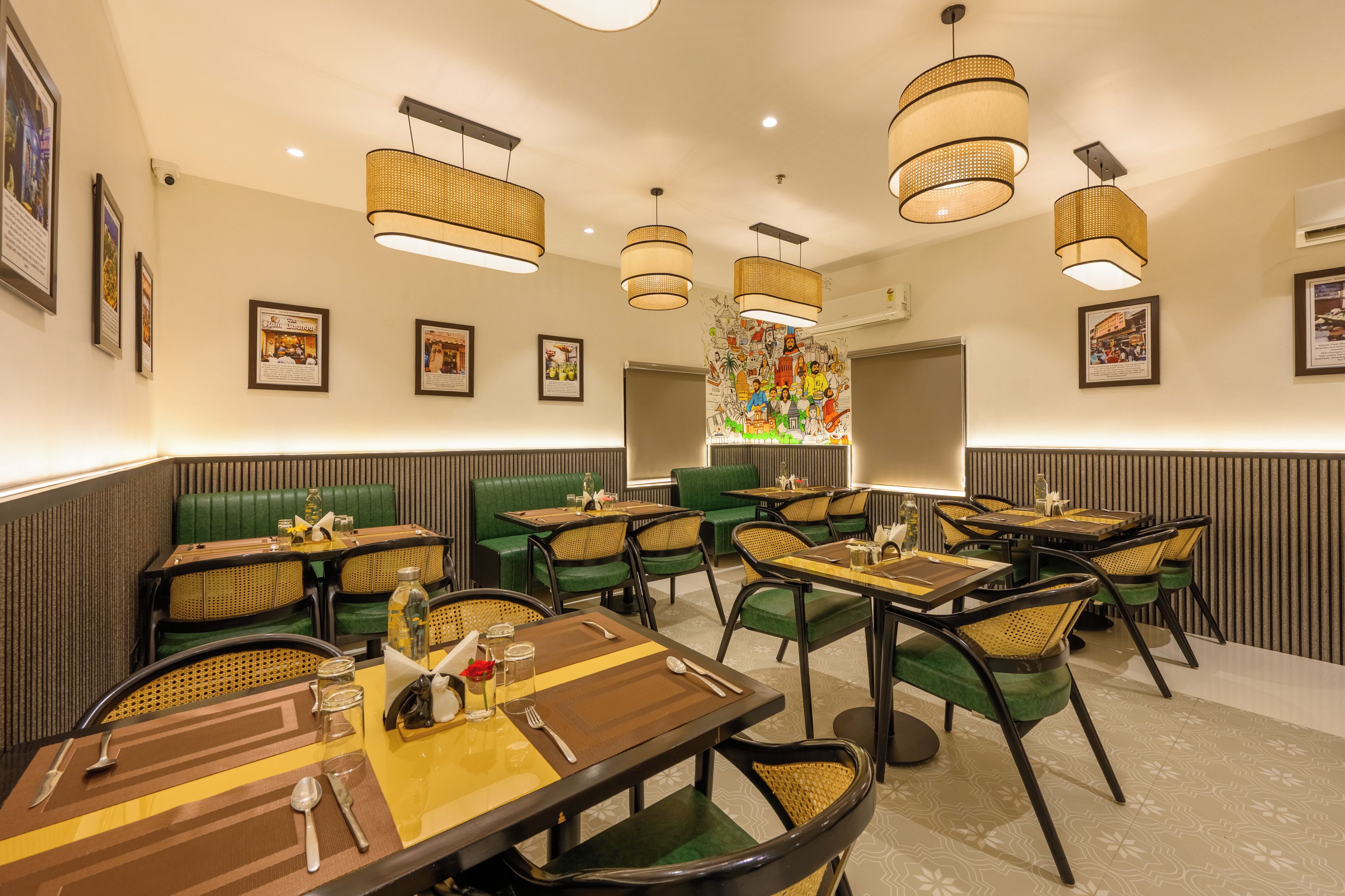 A restaurant with multiple dining tables, green upholstered booths, and hanging wicker lamps.