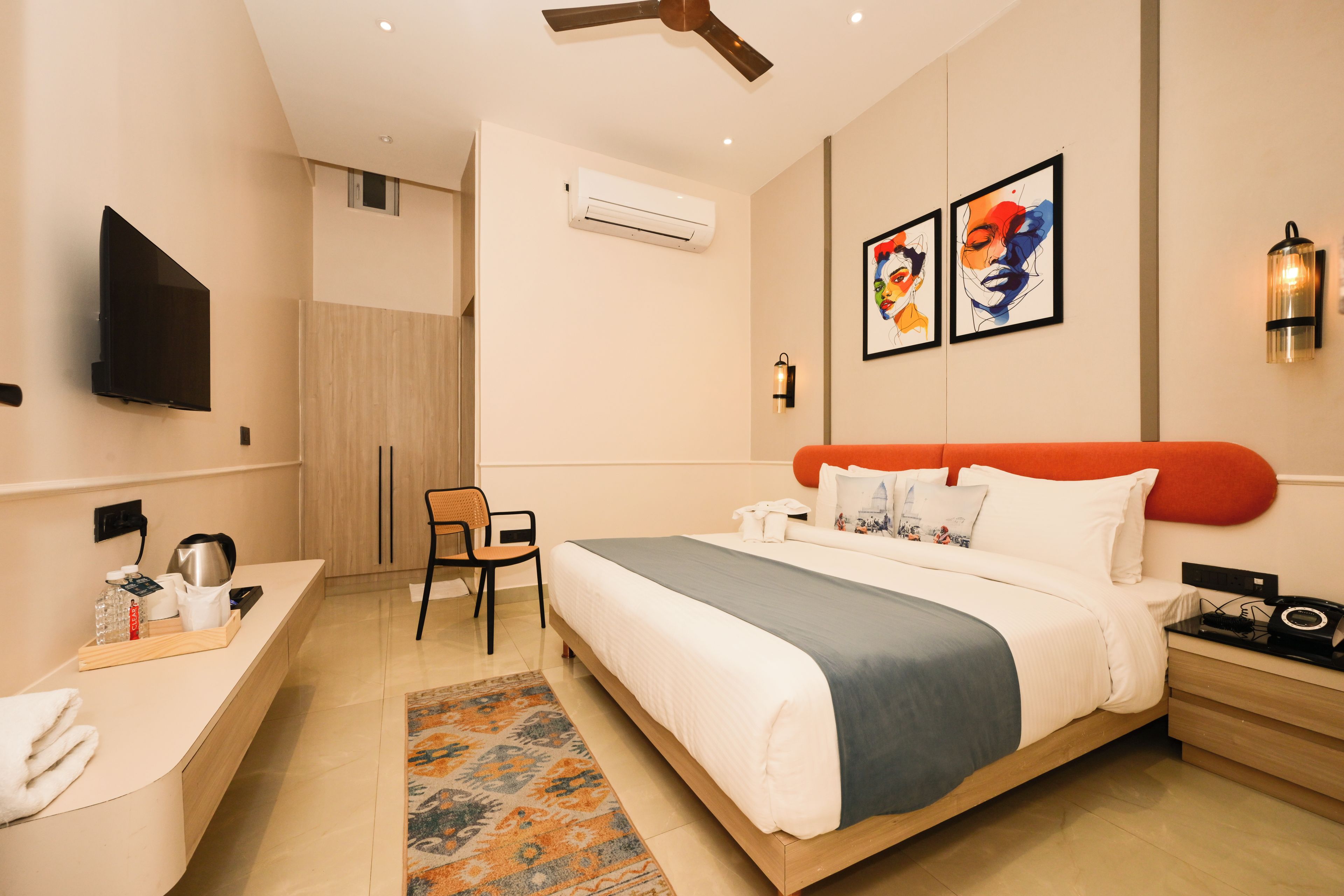 Una camera d'albergo moderna con un letto, un comodino, una sedia e un'opera d'arte appesa al muro.