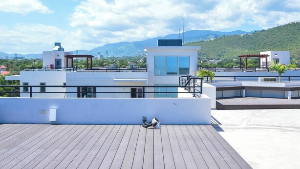 Una terraza en la azotea con vistas a un paisaje urbano y montañas.
