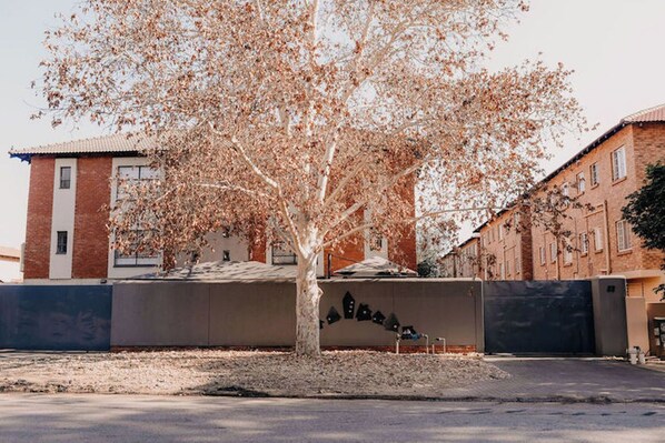 A tree-lined street with a building featuring a brick facade and a flat roof.