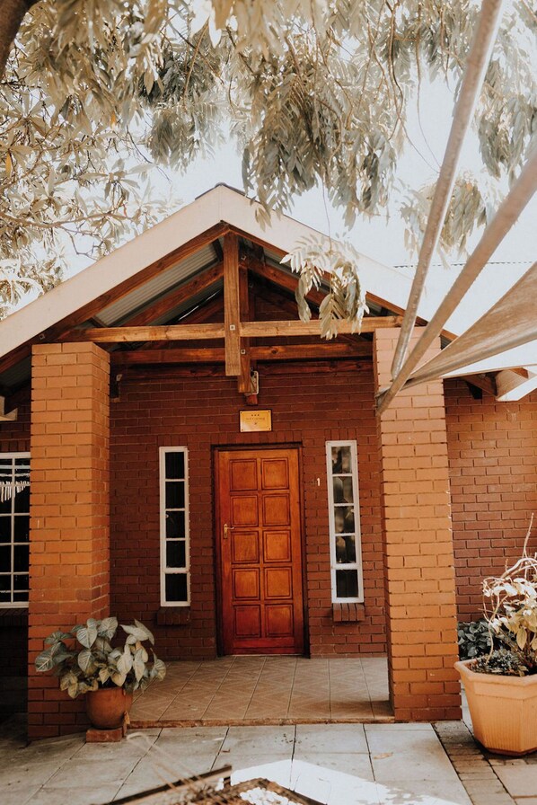 A wooden building with a brick facade, a wooden door, and a small window. - La Rona Hospitality Services (Rustenburg)