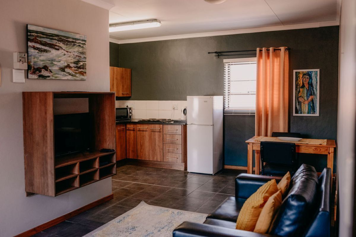 A compact living space with a kitchen, a dining area, and a seating area with a sofa.