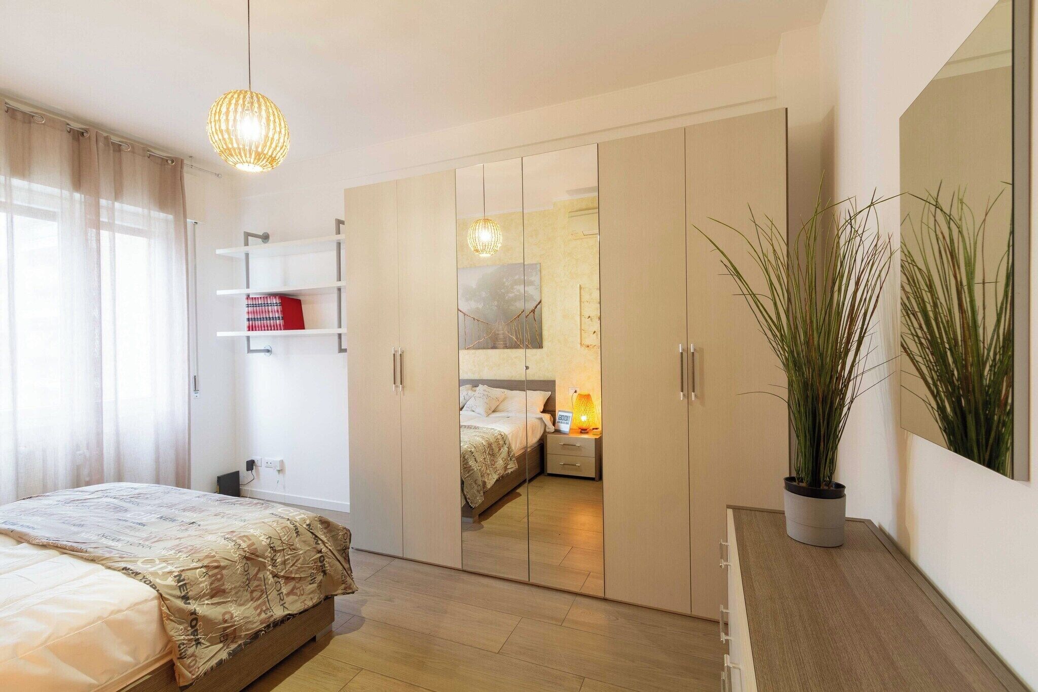 Une chambre à coucher avec un lit, une armoire, une table de chevet, une lampe et une plante en pot.