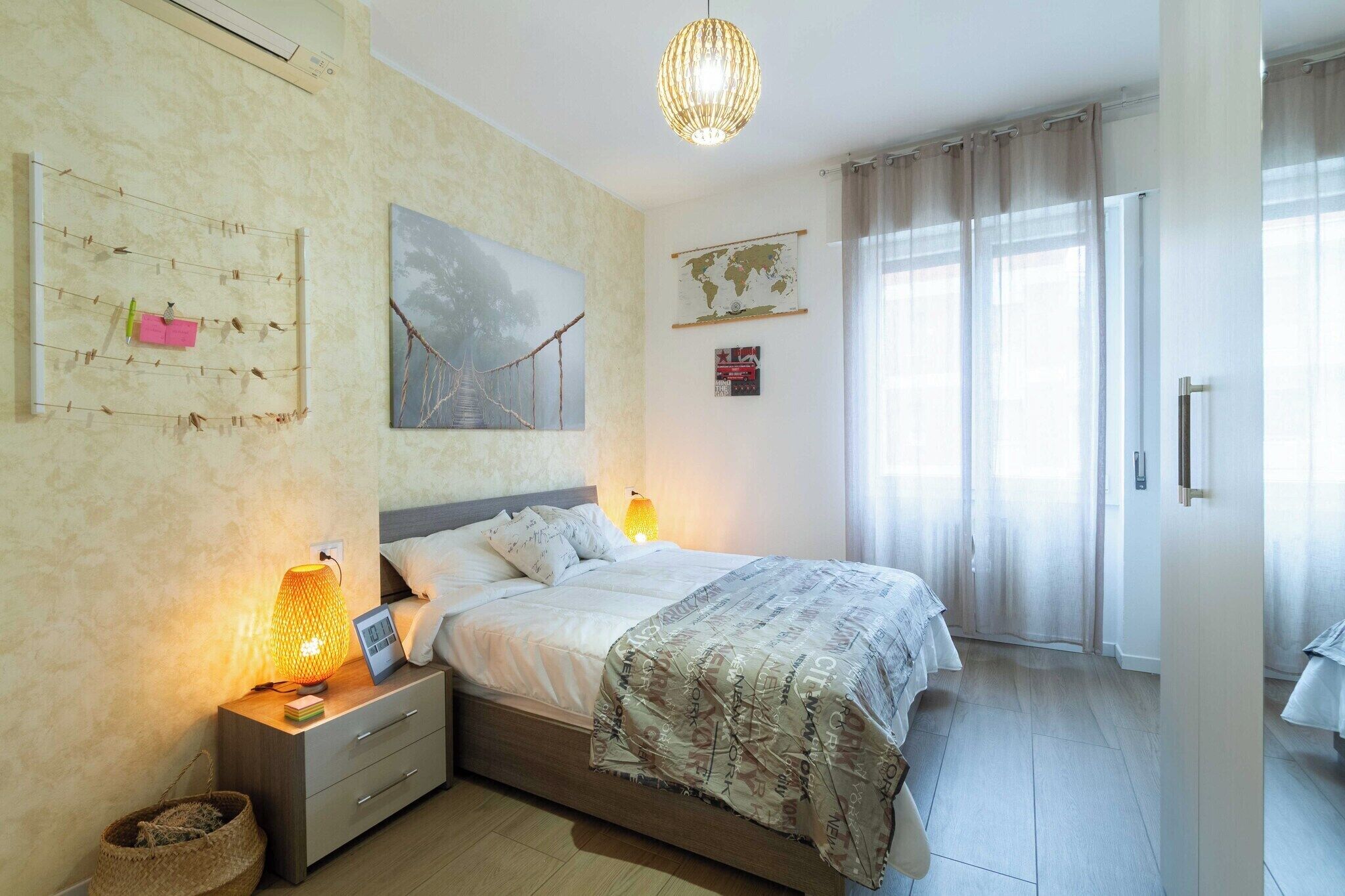A bedroom with a bed, bedside lamps, a wall-mounted globe, and a window with curtains.