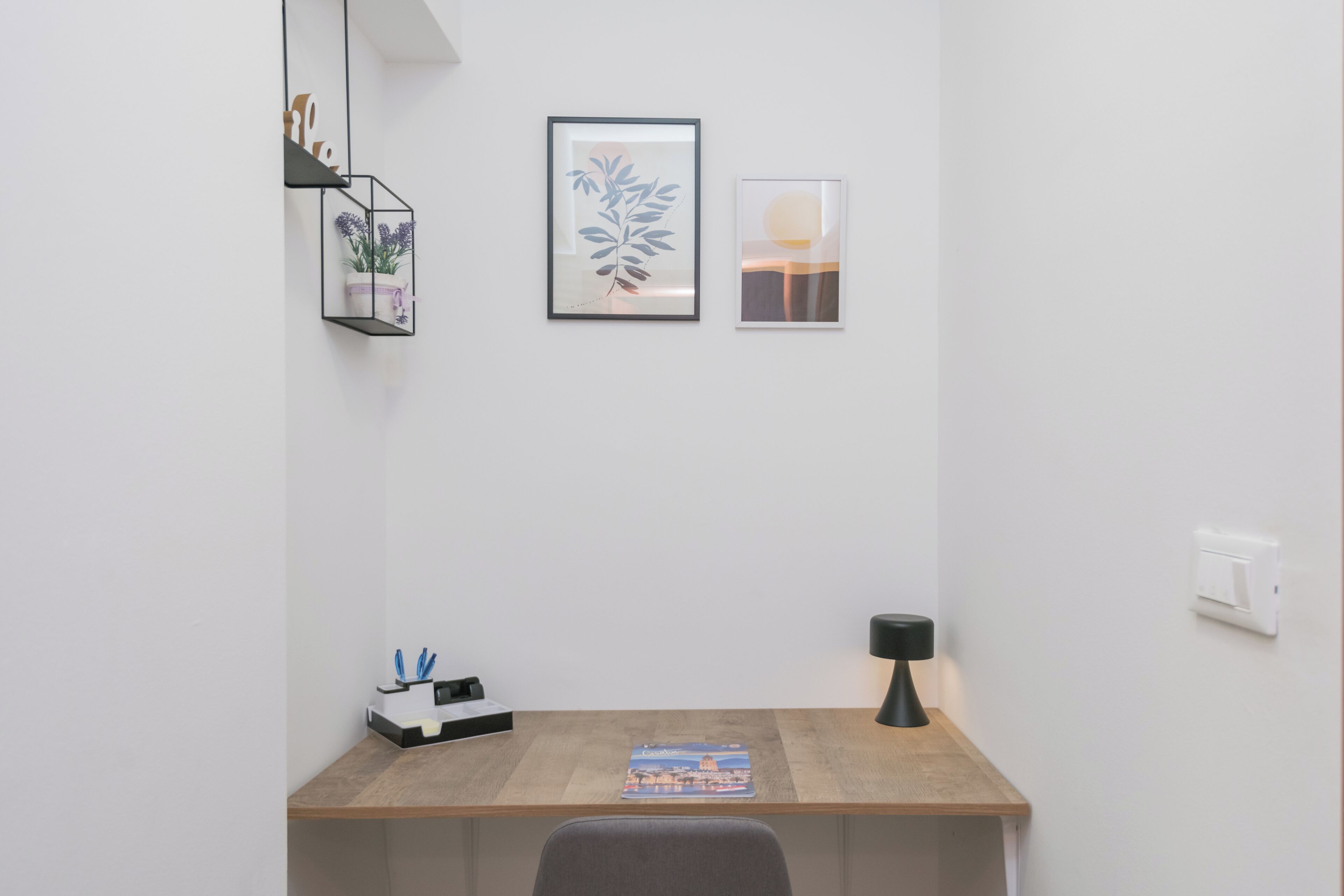 Un bureau au design minimaliste, avec un bureau en bois, une plante en pot et une lampe.