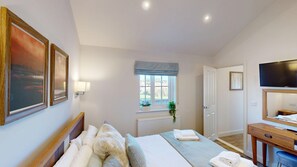 A hotel room with a bed, a desk, a television, and a window with a view of the outdoors. - A luxury 2 bed lakeside lodge that sleeps 4 guests  in 2 bedrooms (Filey)