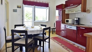 Une cuisine compacte avec un coin repas, comprenant un four à micro-ondes, une machine à café et un meuble rouge.