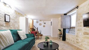 Un salón acogedor con un sofá verde, una mesa redonda de café negra y una pared de piedra.