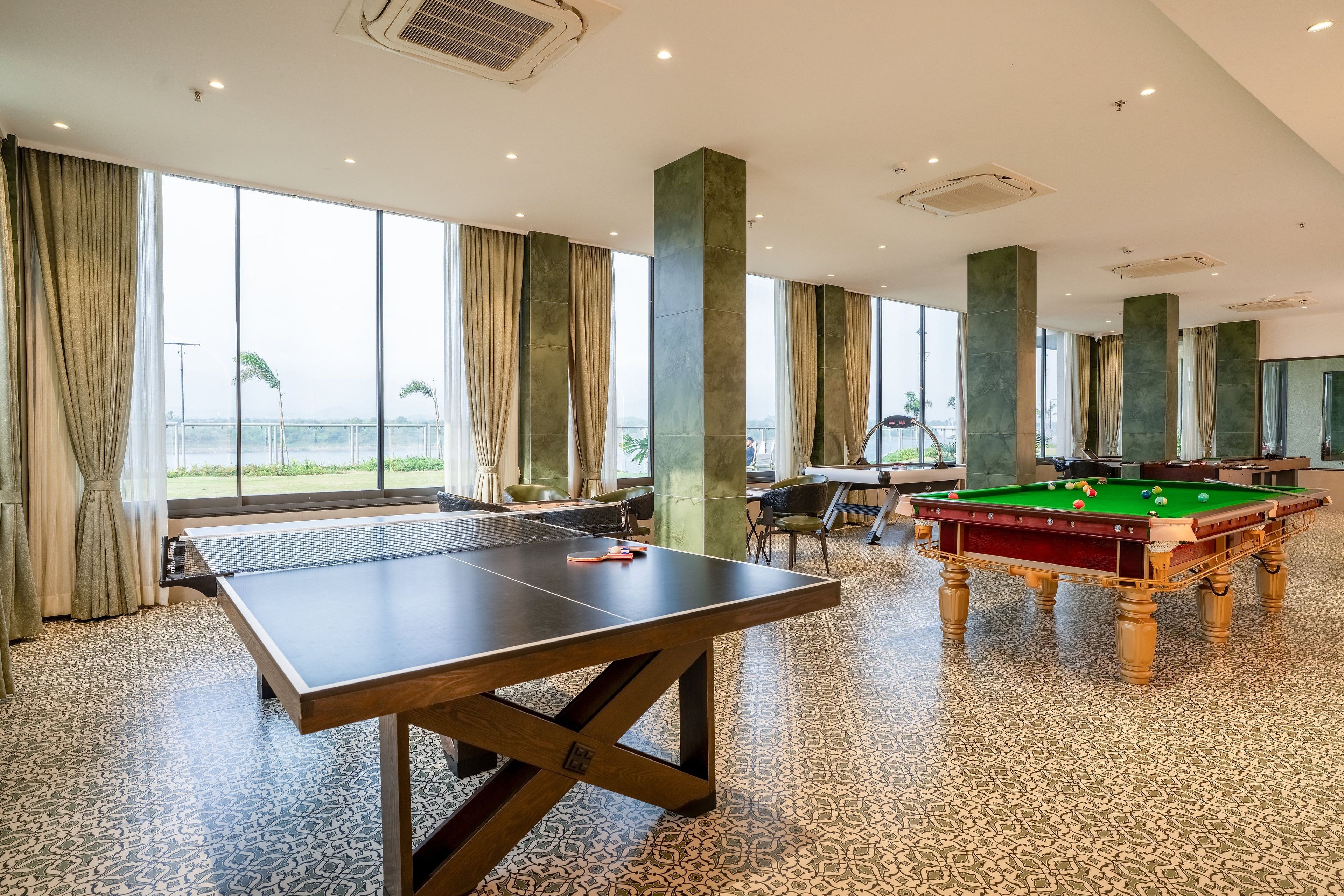 Una habitación amplia con mesa de ping pong, mesa de billar y ventanas grandes que ofrecen vistas.