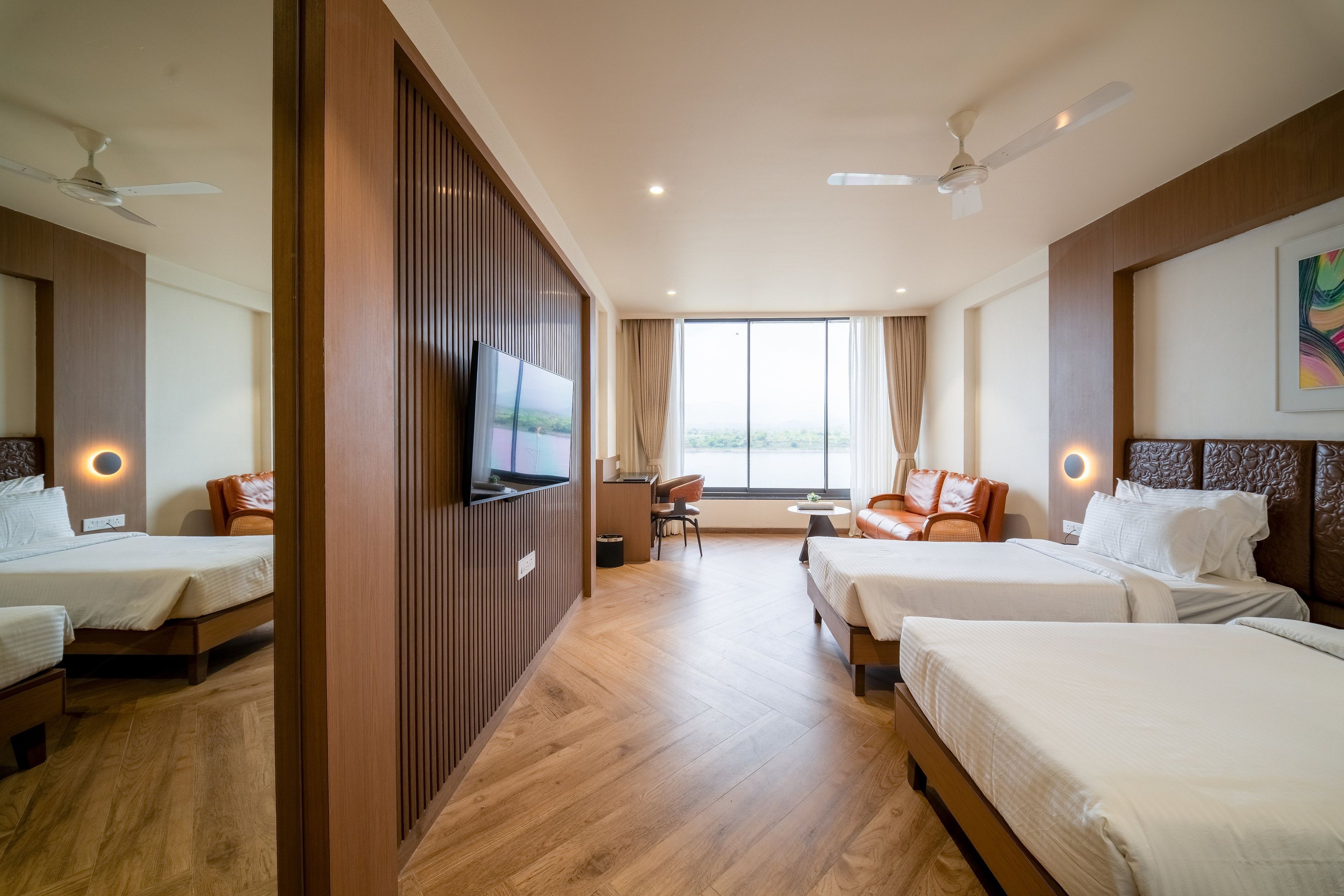Habitación de hotel con dos camas, un televisor, un escritorio y una ventana con vistas.
