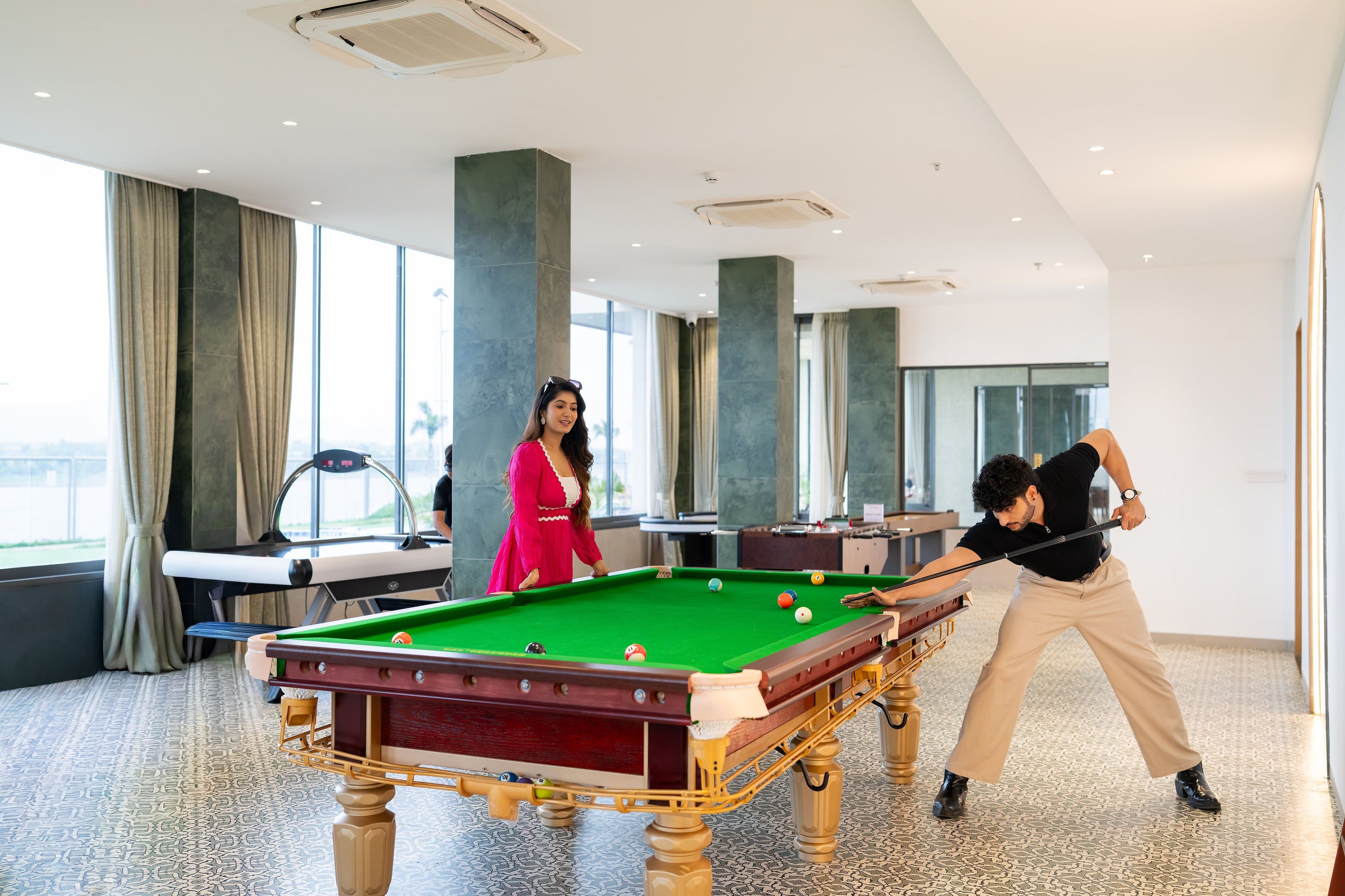 Une table de billard dans une pièce dotée de grandes fenêtres donnant sur l’extérieur.
