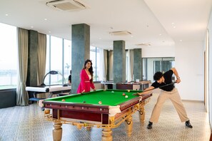 Una mesa de billar en una habitación con ventanas amplias y vistas al exterior.