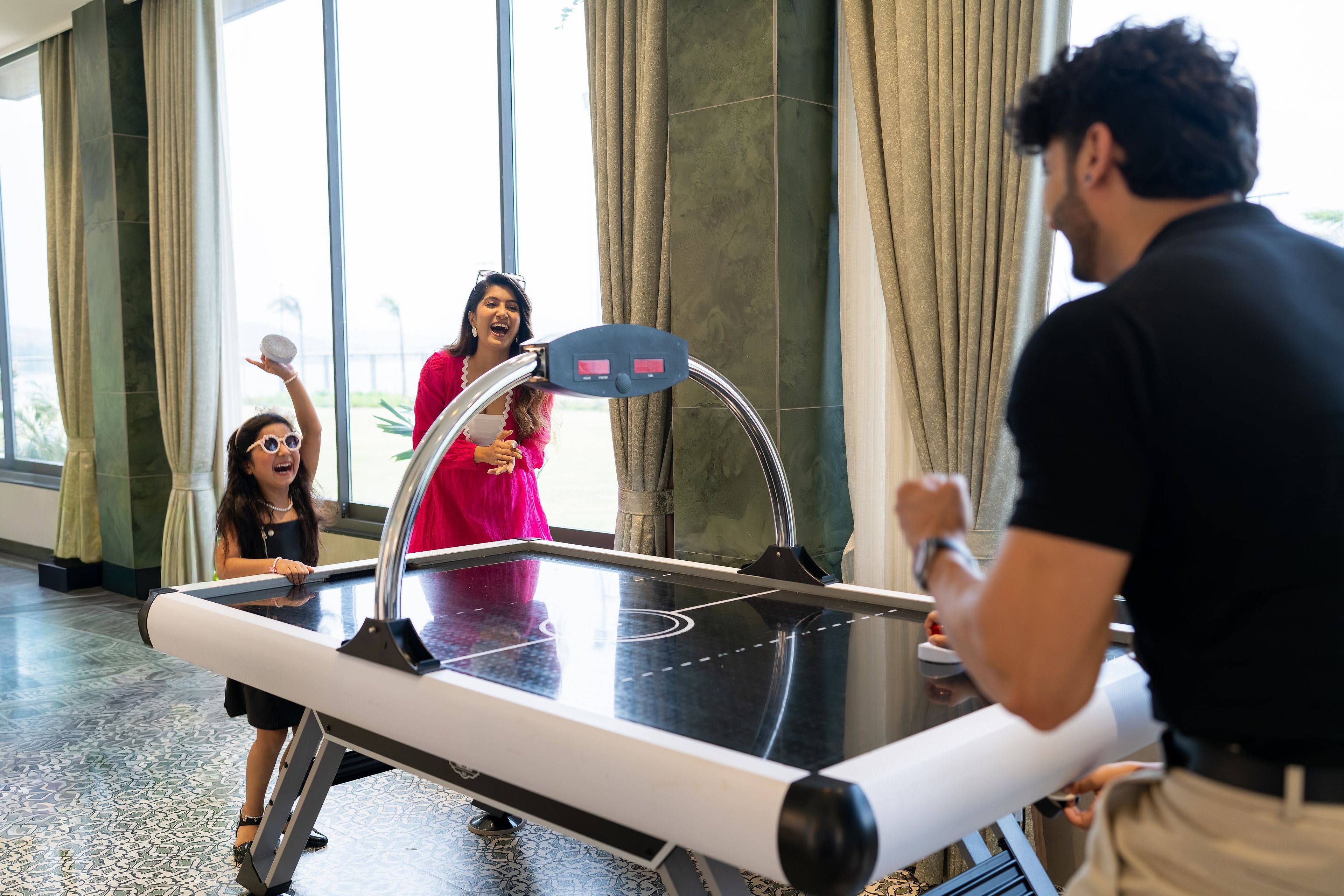 A group of people playing table tennis in a spacious indoor area with large windows and a modern design.