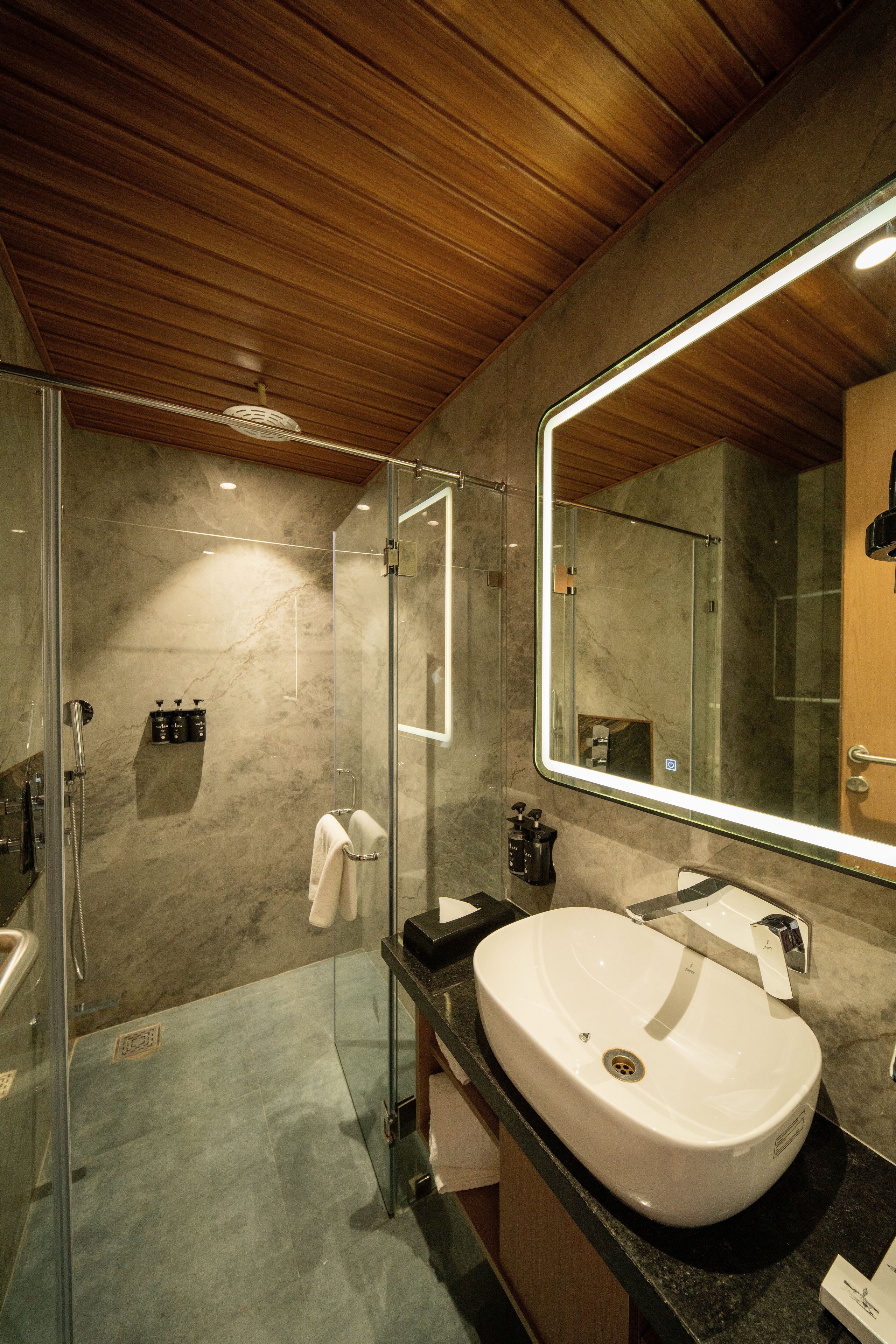 A modern bathroom with a glass-enclosed shower, a white sink, and a large mirror.