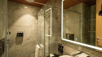 Un baño moderno con ducha de vidrio, un lavamanos blanco y un espejo grande.