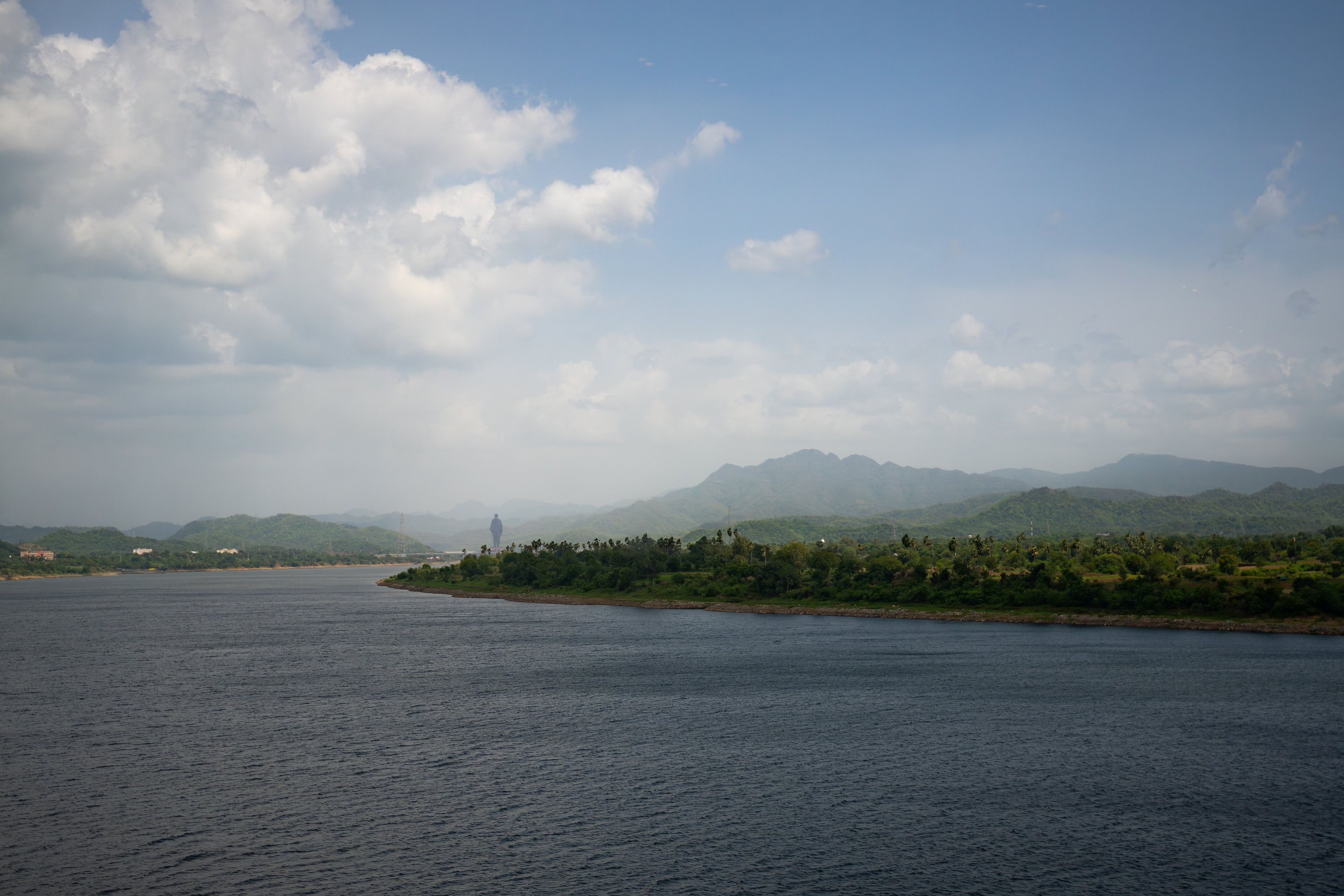 A river with a distant mountain range and a person standing on the bank.