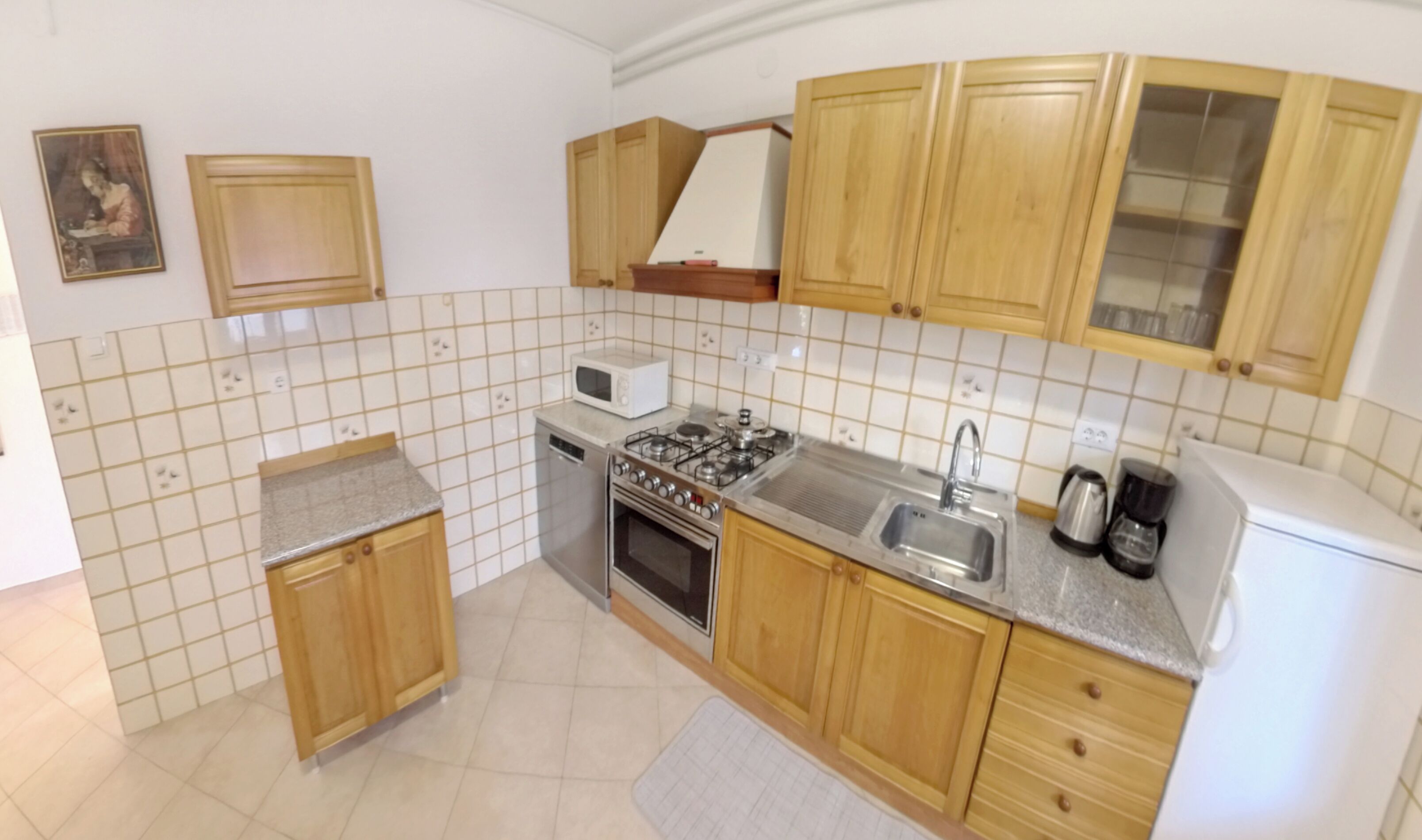 Una cocina con armarios de madera, microondas, estufa, fregadero y refrigerador.