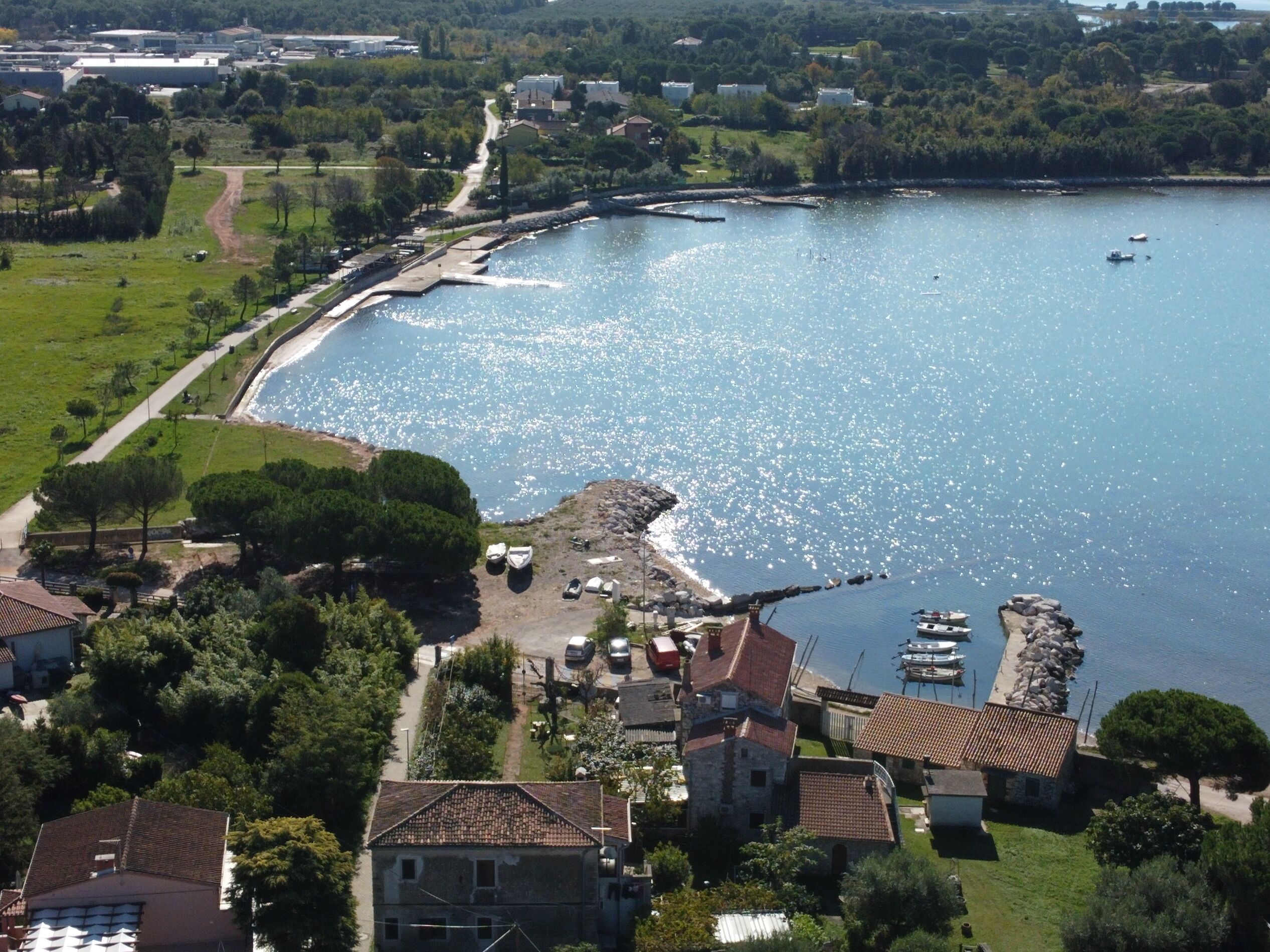 A coastal town with a marina, houses with red-tiled roofs, and a clear view of the sea.
