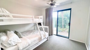 A room with a bunk bed, a ceiling fan, and a sliding glass door leading to an outdoor area. - Breakers Block 4 Unit 1 - Lifestyle Yamba (YAMBA)