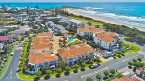 A coastal residential area with houses, a beach, and a clear sky. - Breakers Block 4 Unit 1 - Lifestyle Yamba (YAMBA)