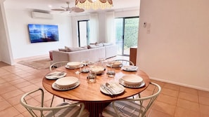 A dining area with a round table set for six, surrounded by chairs. - Breakers Block 4 Unit 1 - Lifestyle Yamba (YAMBA)