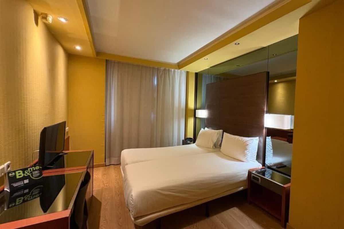 Een hotelkamer met een bed, een bureau, een stoel, een televisie en een nachtkastje.