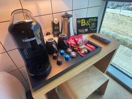 Uma cozinha compacta com cafeteira, xícaras de café, chaleira, termo e petiscos.