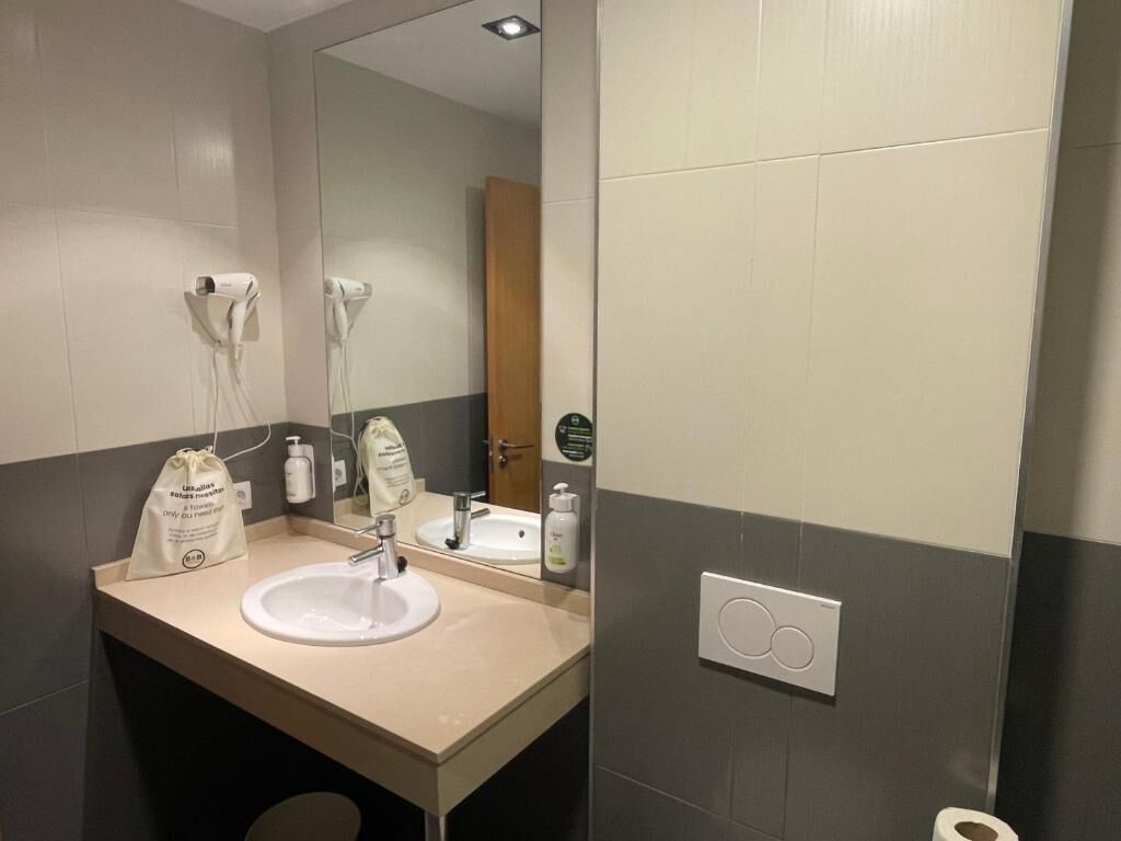 A modern bathroom with a beige sink, a mirror, and a hairdryer.