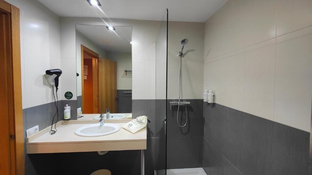 Un baño moderno con ducha de vidrio, tocador doble y espejo.