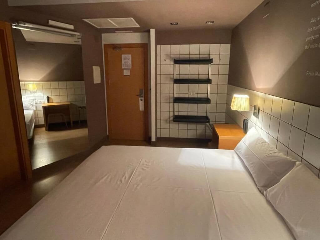Een hotelkamer met een groot bed, een nachtkastje, een wandplank en een deur naar een badkamer.