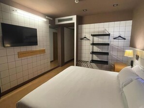 A hotel room with a bed, a TV mounted on the wall, a towel rack, and a heater. - B&B HOTEL Miranda de Ebro (Ribera Baja)