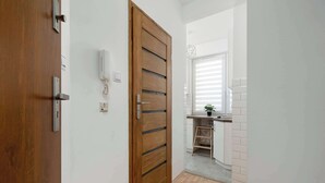Un corridoio con una porta in legno, un telefono e un angolo cottura con lavello e piano di lavoro.